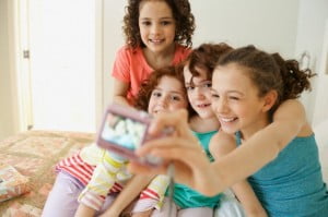Young girls taking pictures at sleepover.